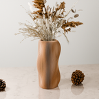 Wooden vase with dried plants and pinecones on a light surface