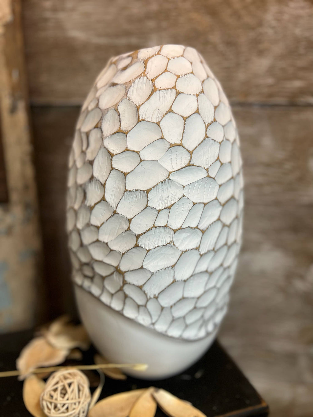 Mosaic-patterned ceramic vase on a wooden surface with a neutral background