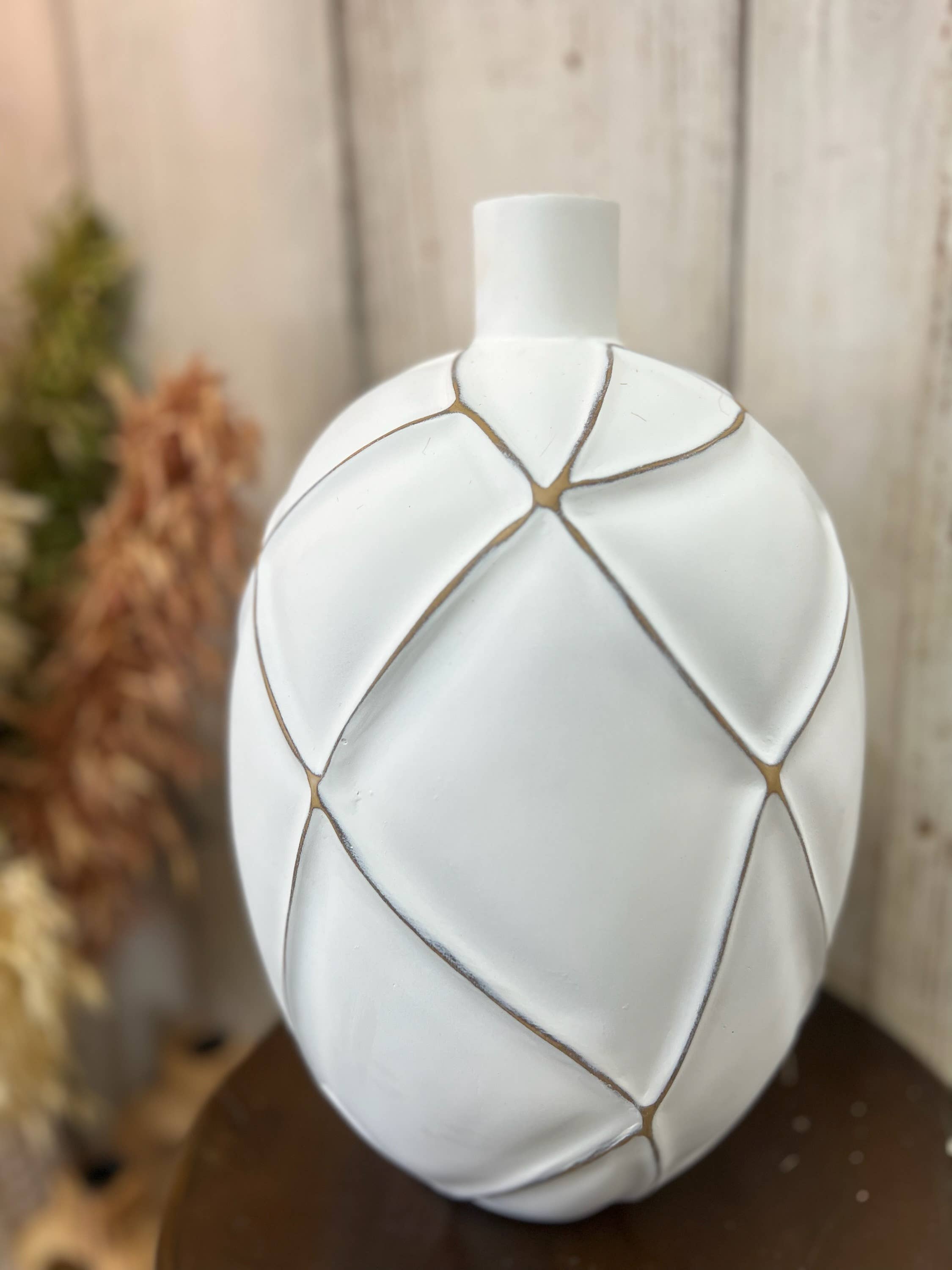 White ceramic vase with geometric design on a wooden surface