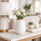 White vase with flowers on a coffee table in a living room setting