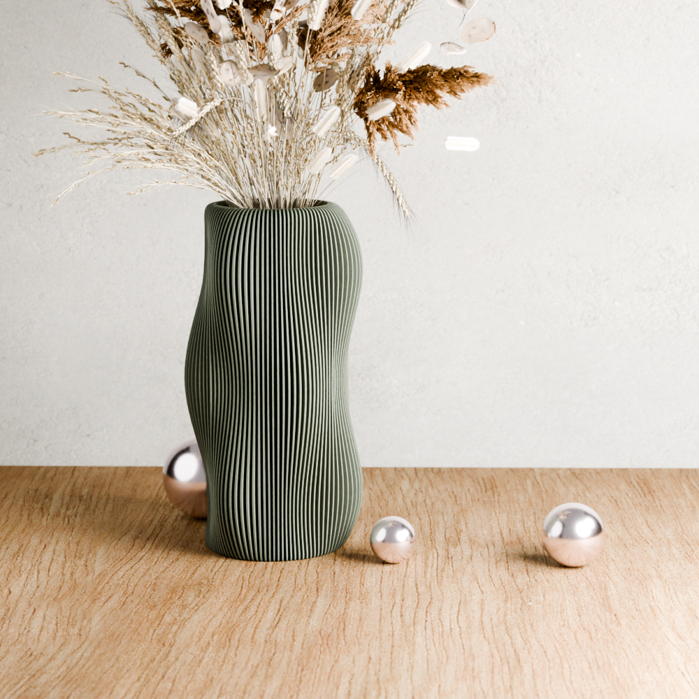 Green textured vase with dried plants on a wooden surface