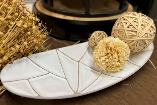 Decorative items including a ball of twine and dried flowers on a white ceramic dish.