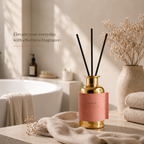 Gold diffuser with pink label on a bathroom counter, text 'Elevate your everyday with effortless fragrance'.