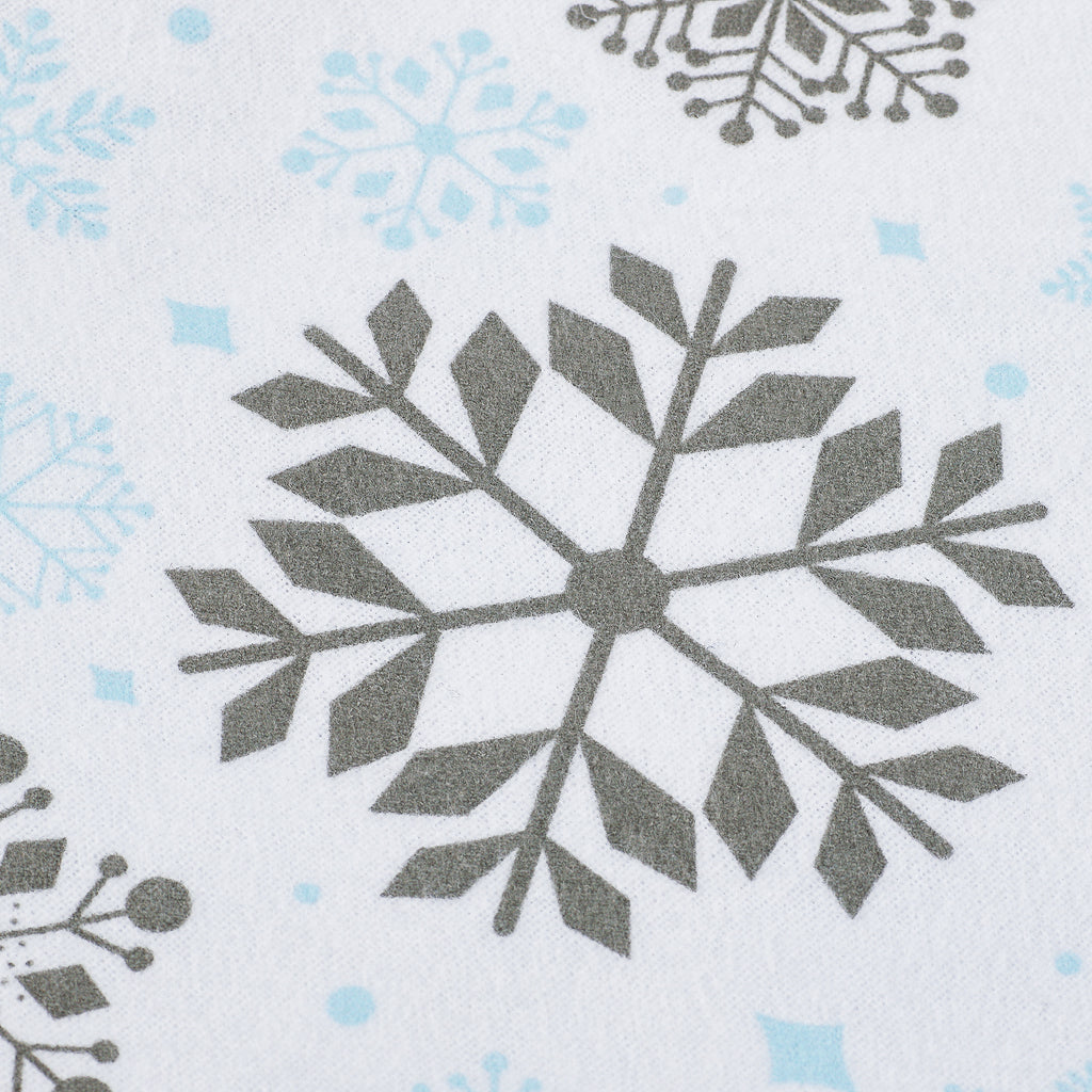 A close-up of a white fabric with a repeating pattern of gray snowflakes and light blue snowflake accents.