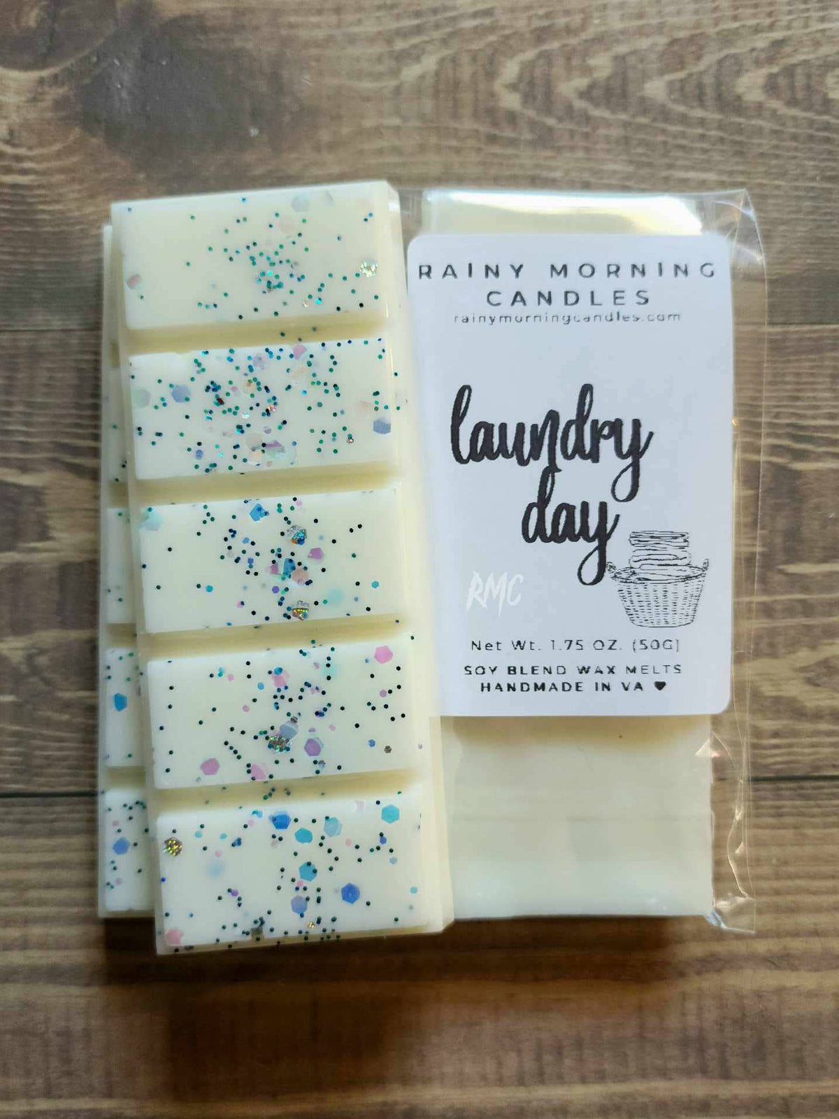 Laundry Day soy wax melt snap bar in clear packaging with the Rainy Morning Candles label; white wax with colorful confetti glitter on a wooden surface.