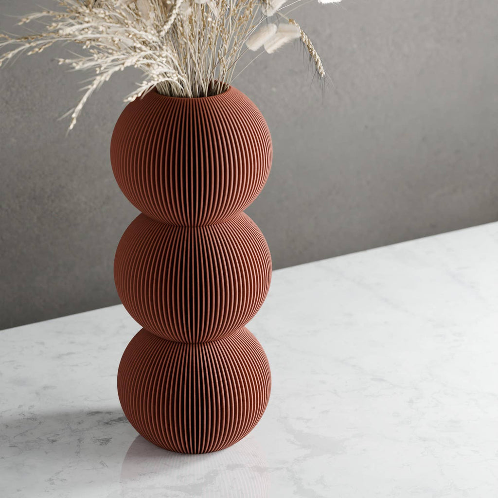 Brown textured vase with dried plants on a white surface and gray background