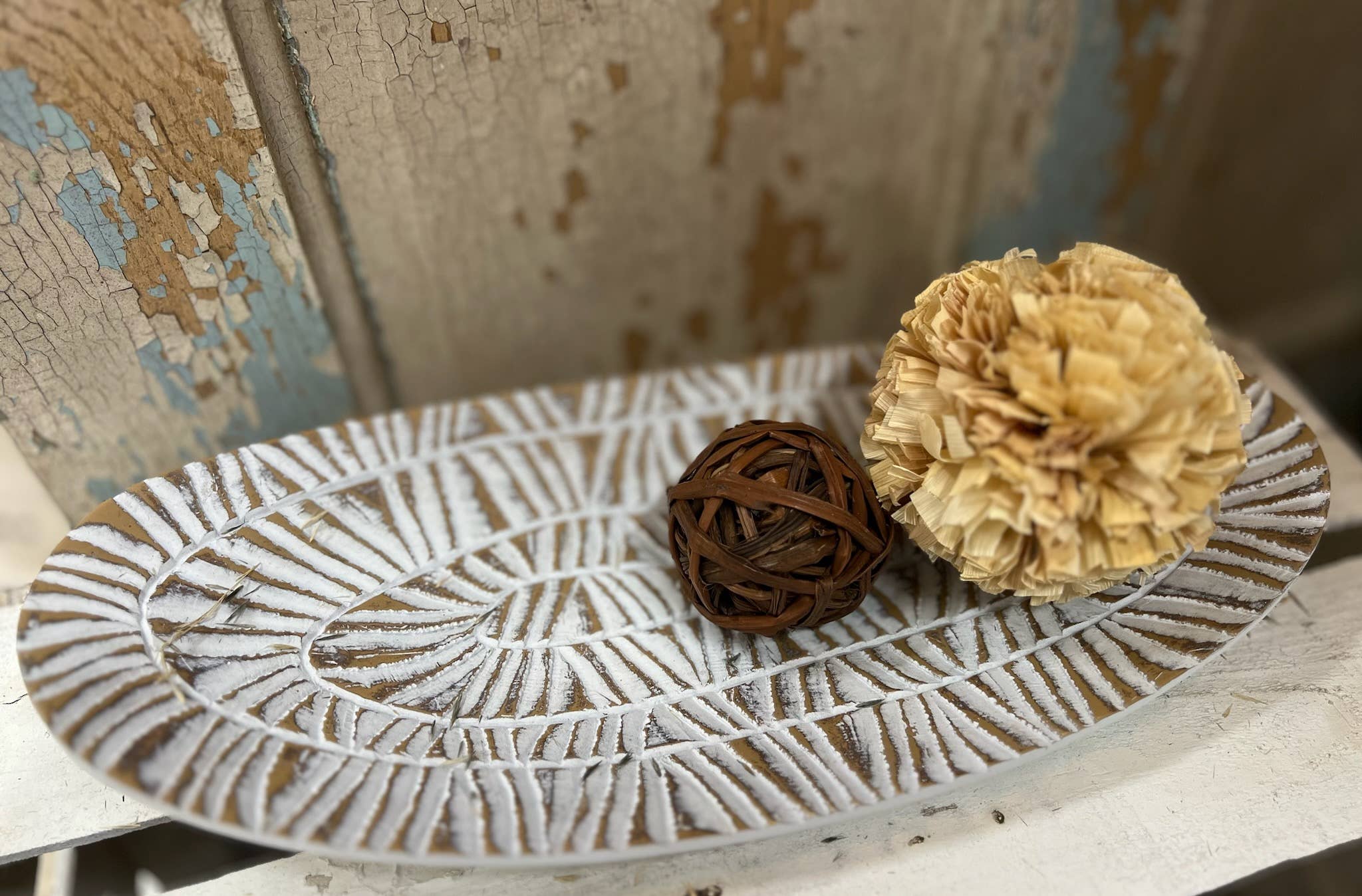 Decorative plate with textured surface featuring a brown ball and beige flower-like object on a rustic background.