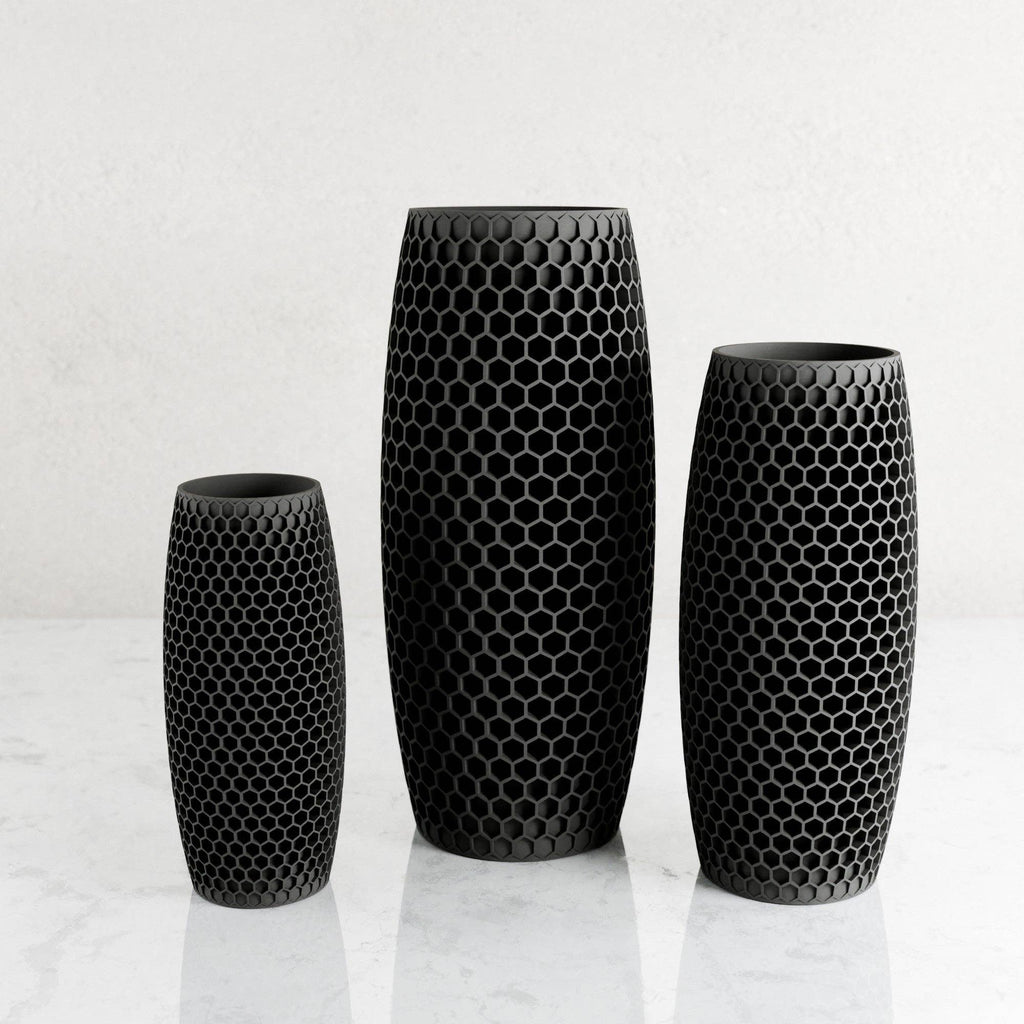 Three black ceramic plastic with a honeycomb pattern, displayed in ascending sizes on a light marble surface against a white background.