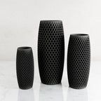 Three black ceramic plastic with a honeycomb pattern, displayed in ascending sizes on a light marble surface against a white background.