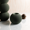 Set of three green textured vases on a light surface with a blurred background