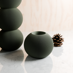 Set of three green textured vases on a light surface with a blurred background