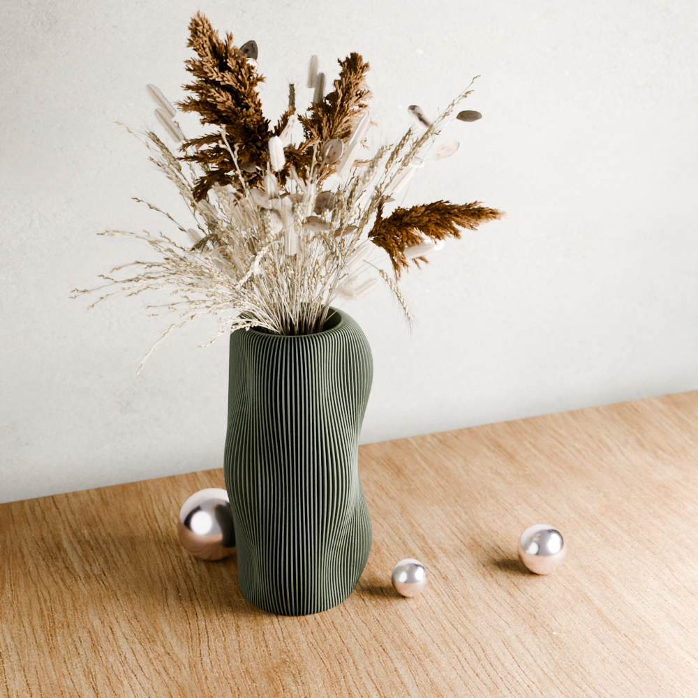Green textured vase with dried plants on a wooden surface