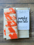 Pumpkin Spice Latte soy wax melt snap bar in clear packaging with the Rainy Morning Candles label; white wax with orange swirls on a wooden surface.