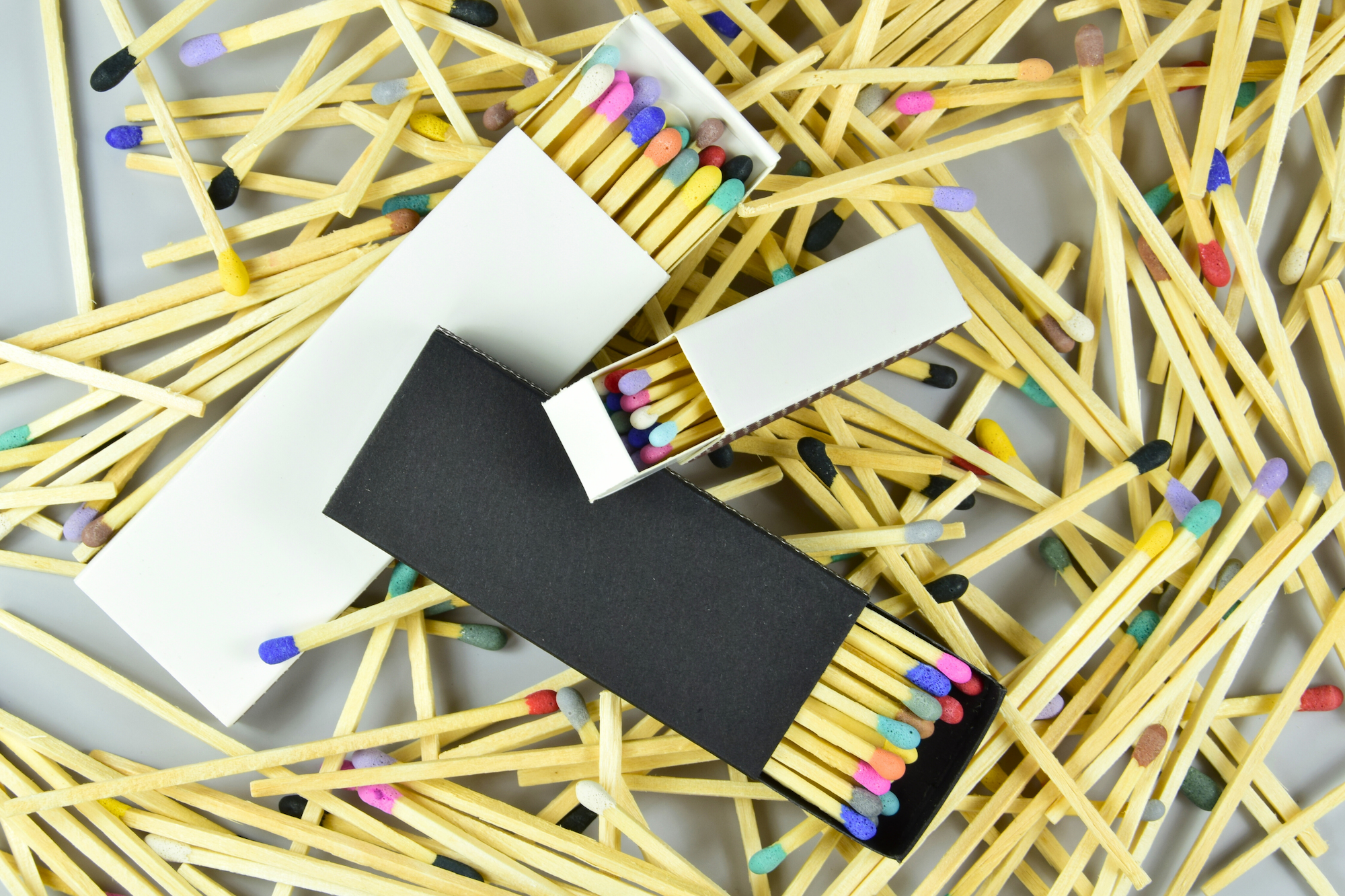 Matches with colorful heads scattered on a white background
