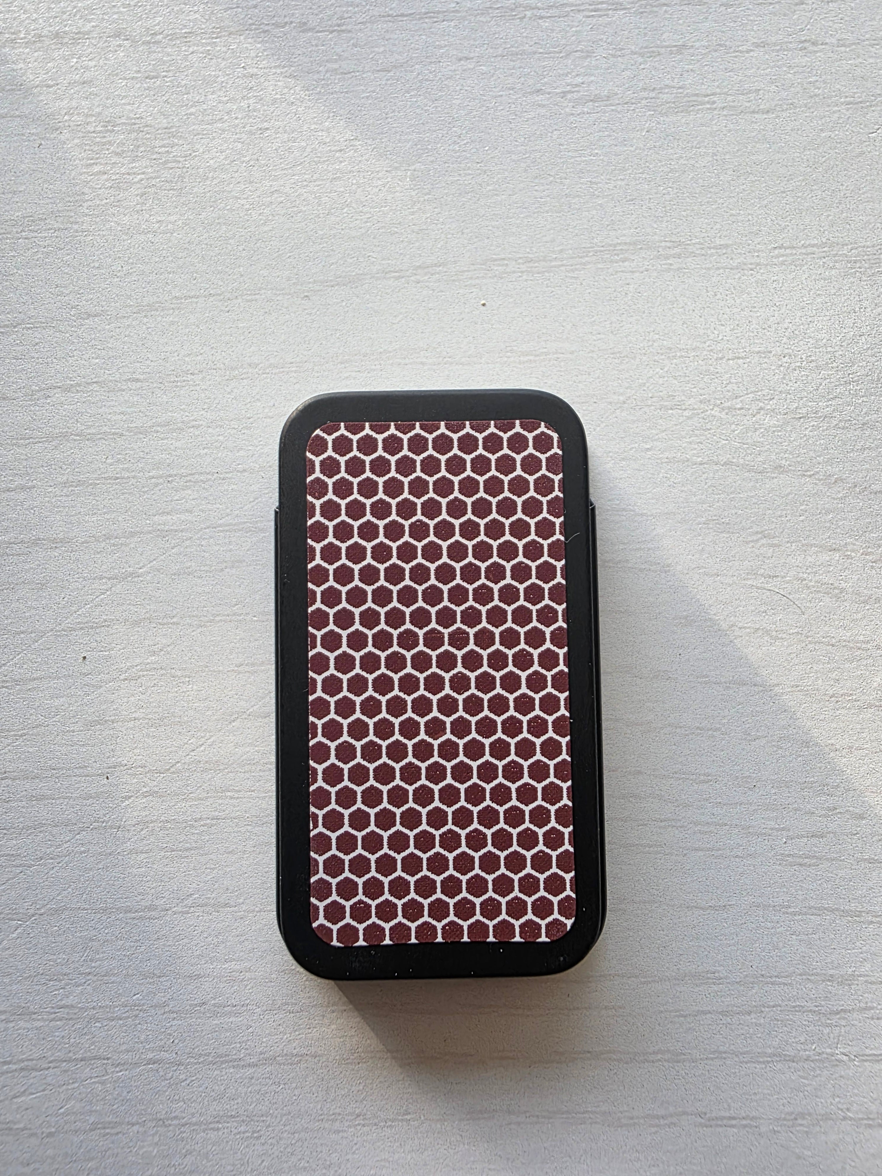 Bottom of decorative match tin showing honeycomb match striker paper strip