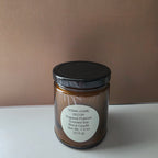 A 7.5 oz scented soy candle in an amber glass jar with a black lid and a white circular label reading 'SOMA HOME DECOR Sugared Pralines Scented Soy Blend Candle'.