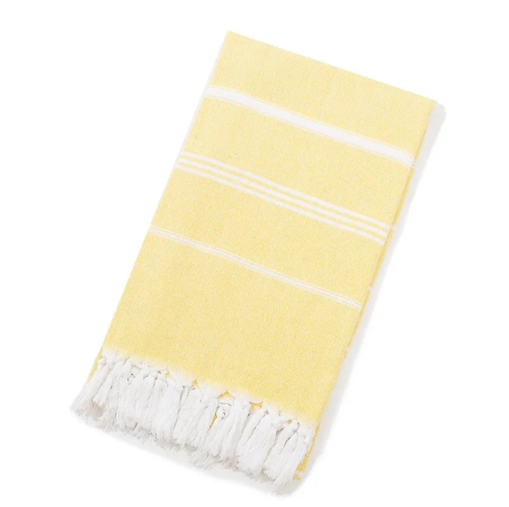 Folded light yellow Turkish beach towel with white stripes and white tassels on white background