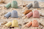 Turkish peshtemal beach towels with matching striped drawstring bags on the beach: green, gray, blue, red, yellow and orange