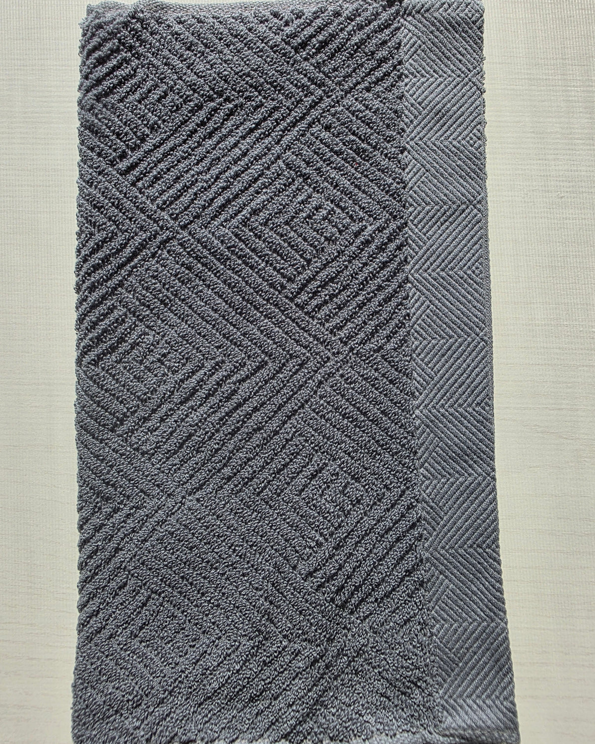 Close-up of dark gray cotton hand towel showing jacquard rhombus weave texture