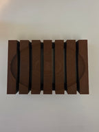 A set of six dark brown wooden blocks with a circular grooved texture, arranged in a row on a plain light background.