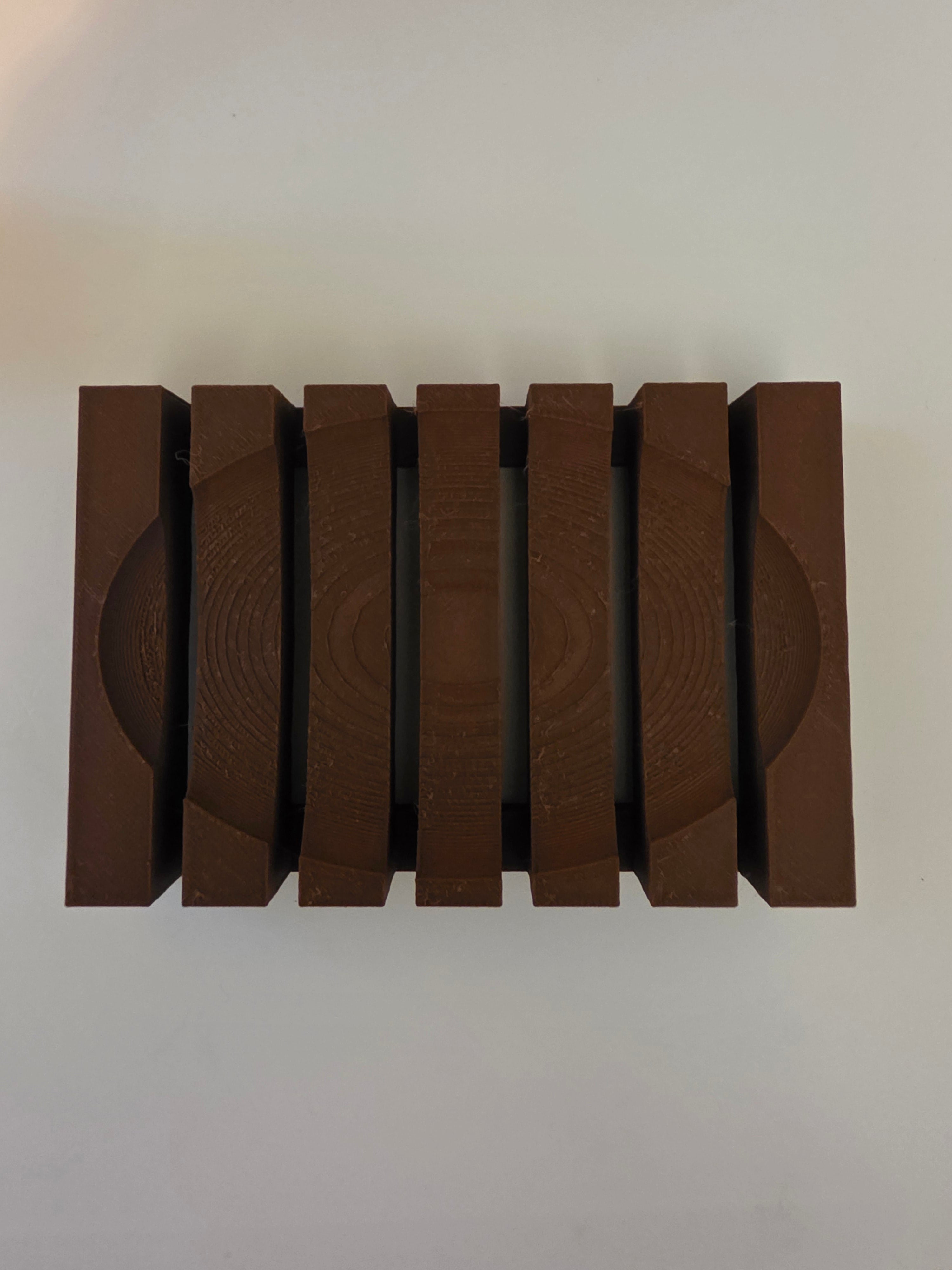 A set of six dark brown wooden blocks with a circular grooved texture, arranged in a row on a plain light background.
