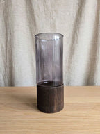 Smoky smooth glass vase on a dark wooden base, studio shot