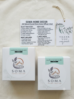 Soma Home Decor natural crystal stone diffuser sheet set, showing the product box, a usage instruction card, and a thank you tag on a textured white fabric background.