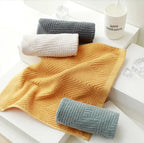 Cotton hand towels in mustard yellow, dark gray, white and sage green with jacquard rhombus weave, styled in a bright bathroom with a Good Morning mug