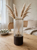 Clear bark-textured glass vase with gold rim styled with pampas grass on a wooden table