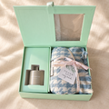Reed diffuser gift set with scarf: open mint green gift box with home fragrance diffuser and blue striped scarf tied with a Thank You tag