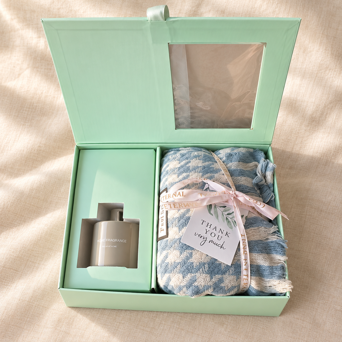 Reed diffuser gift set with scarf: open mint green gift box with home fragrance diffuser and blue striped scarf tied with a Thank You tag