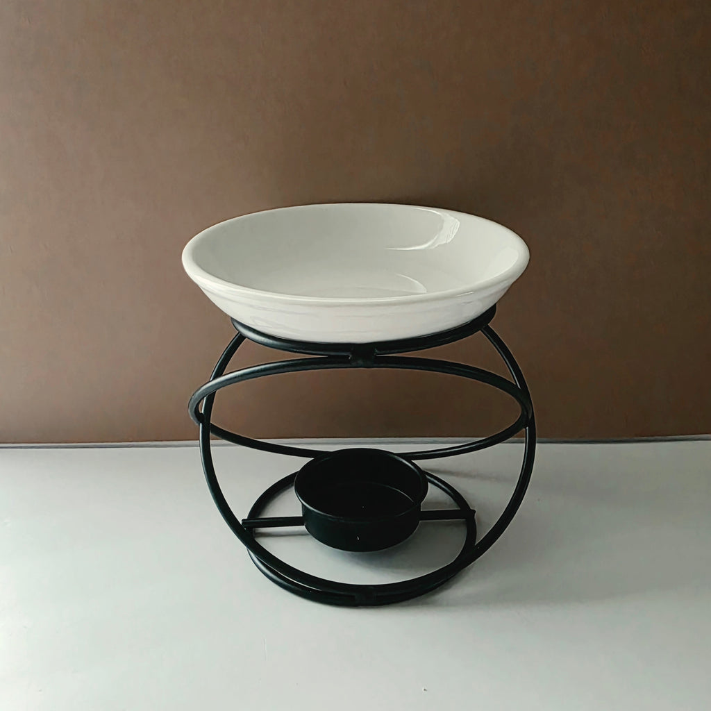 A white ceramic bowl elevated on a black metal stand with a circular base, photographed against a plain brown wall and white surface.
