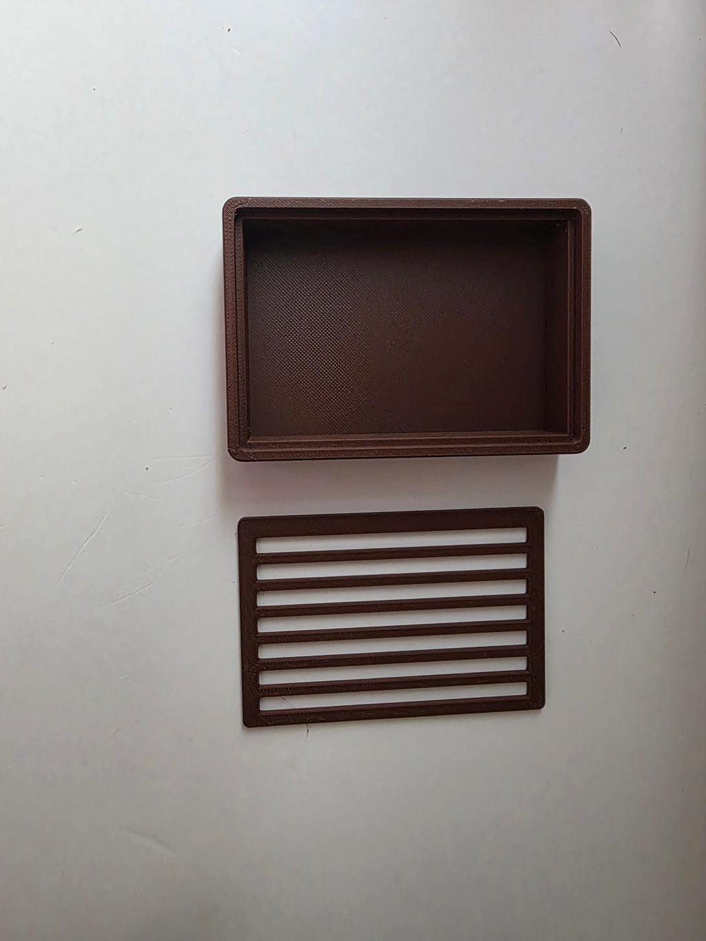 A dark brown rectangular tray with a textured interior and a matching rectangular slatted insert, displayed on a plain off-white background.