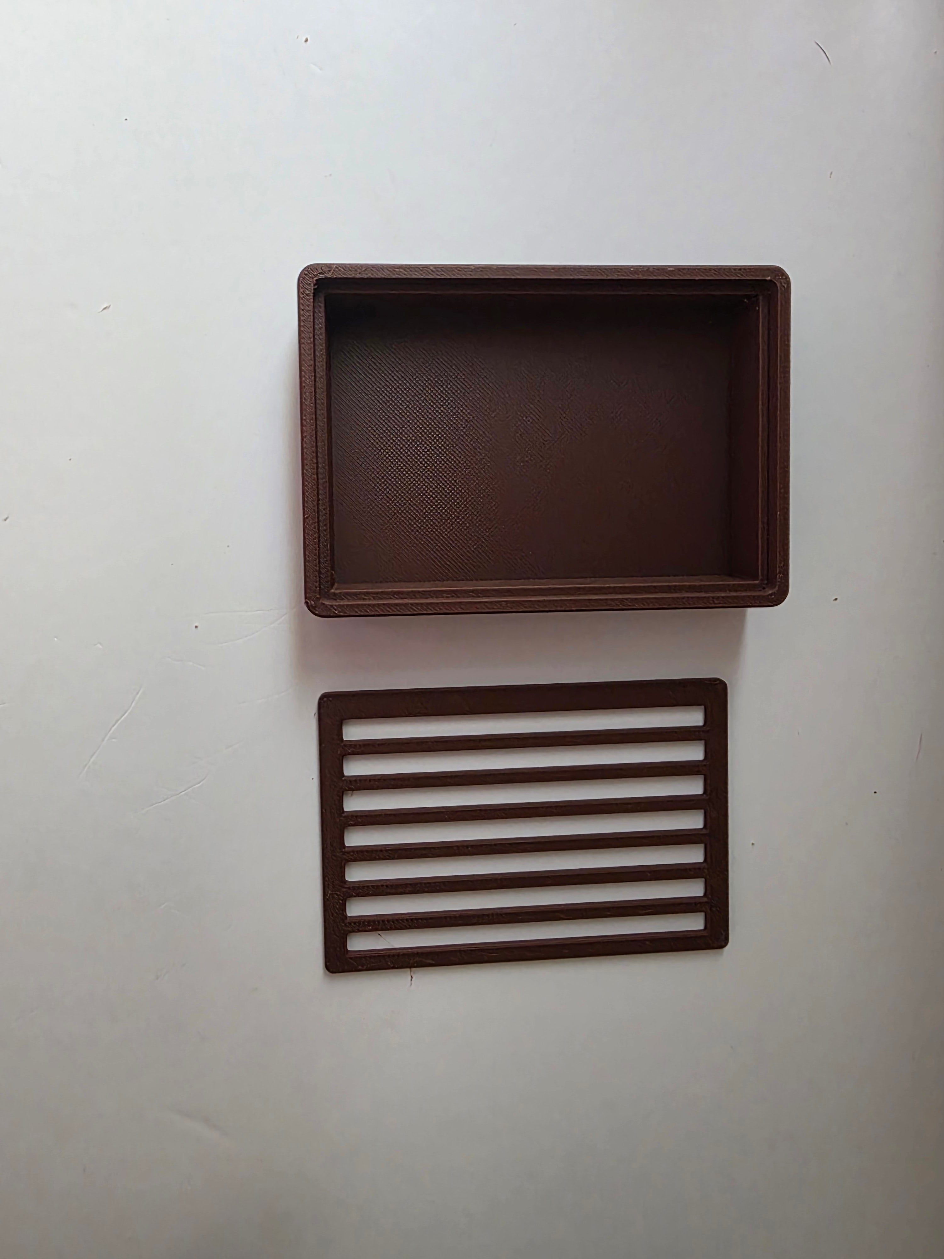 A dark brown rectangular tray with a textured interior and a matching rectangular slatted insert, displayed on a plain off-white background.