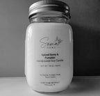 A handpoured soy candle in a clear glass mason jar with a silver metal lid, featuring a white label with black text that reads 'Soma Home' and 'Spiced Berry & Pumpkin'.