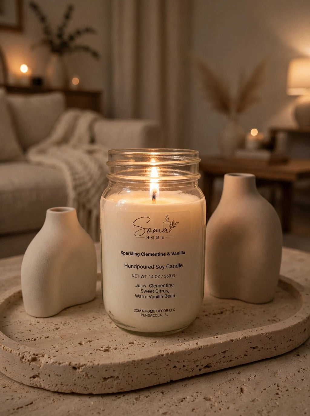 Lit Sparkling Clementine and Vanilla soy candle in a 14 oz mason jar on a stone tray with beige ceramic vases