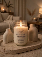 Lit Sparkling Clementine and Vanilla soy candle in a 14 oz mason jar on a stone tray with beige ceramic vases