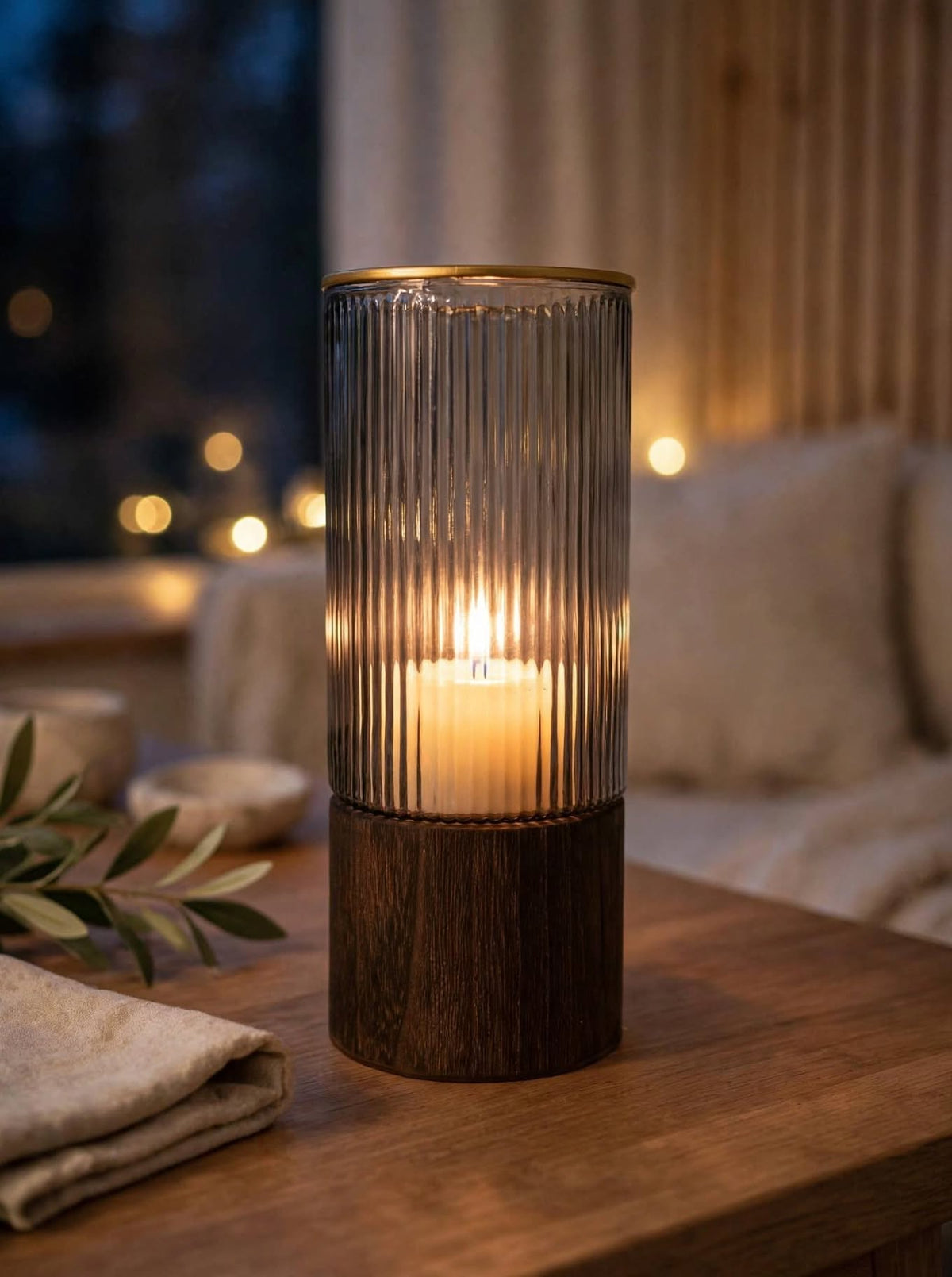 Smoky ribbed glass vase glowing with a lit candle inside at night