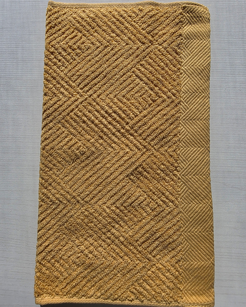 Close-up of dark yellow cotton hand towel showing jacquard rhombus weave texture