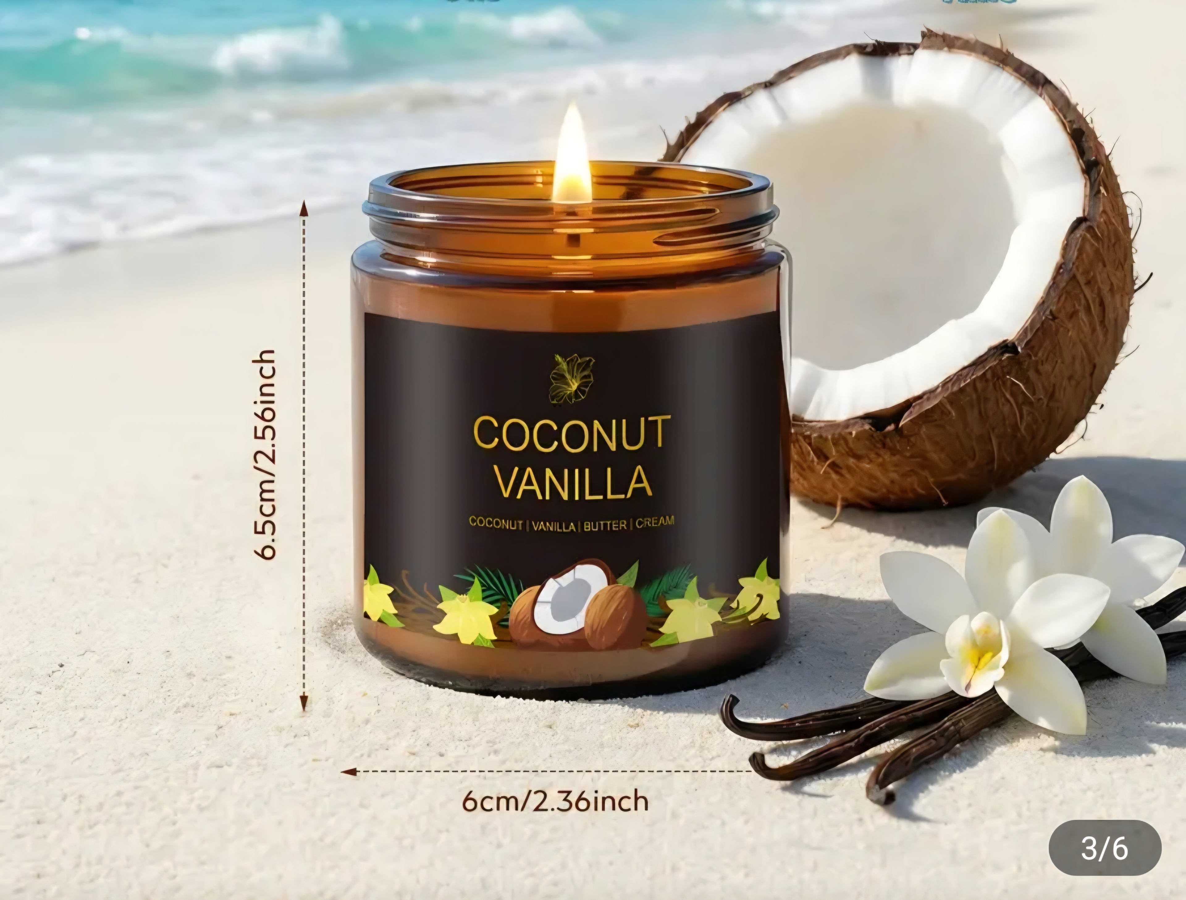 A lit amber glass candle jar labeled 'Coconut Vanilla' sits on a sandy beach with a half coconut, vanilla beans, and white flowers in the background. Measurement text showing 6.
