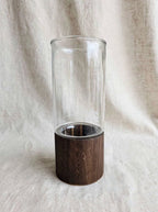 Clear smooth glass vase on a dark wooden base, studio shot