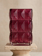 Magenta square geometric glass vase with ice-crackle texture, front view on a stone pedestal