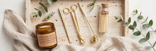 Candle Ritual gift set flat lay: amber jar candle, gold trimmer, snuffer, dipper and matches bottle on a travertine tray