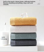 Stack of four folded cotton hand towels in mustard yellow, white, sage green and dark gray with jacquard rhombus weave