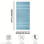 A light blue and white striped bath mat with fringe on the top and bottom, shown with dimension labels of 180CM by 90CM on a white background, with care icons at the bottom.