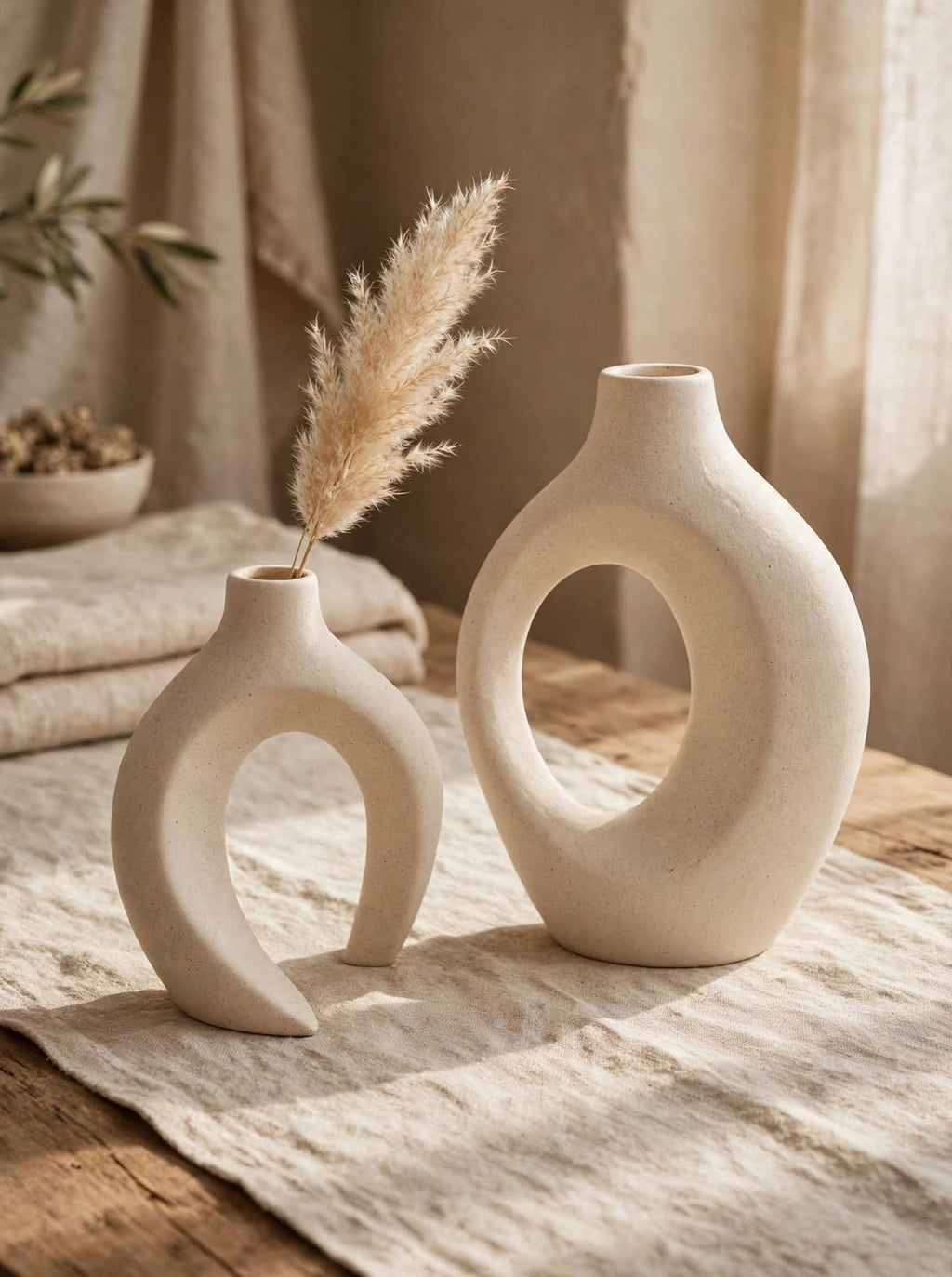 Matte white interlocking ceramic vases with pampas grass on a rustic wooden table