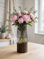 Smoky smooth glass vase on wooden base styled with pink peonies and eucalyptus