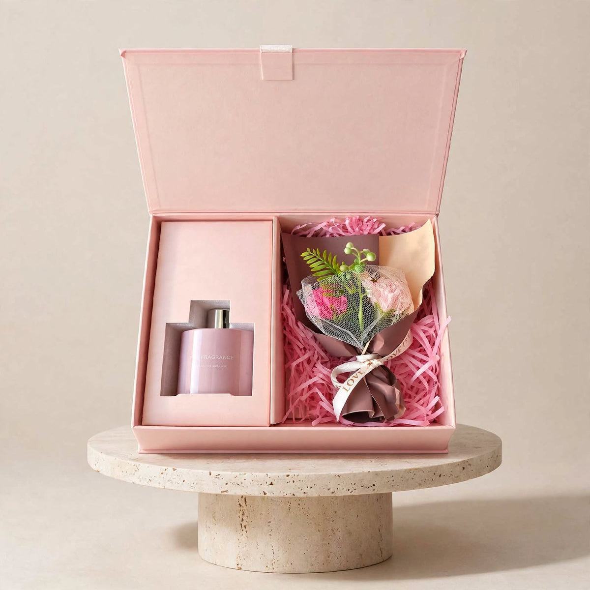 Reed diffuser gift set with bouquet: open pink gift box with diffuser and flower bouquet on a stone pedestal