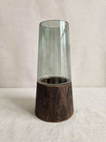 Smoky green glass vase on a dark wooden base, studio shot