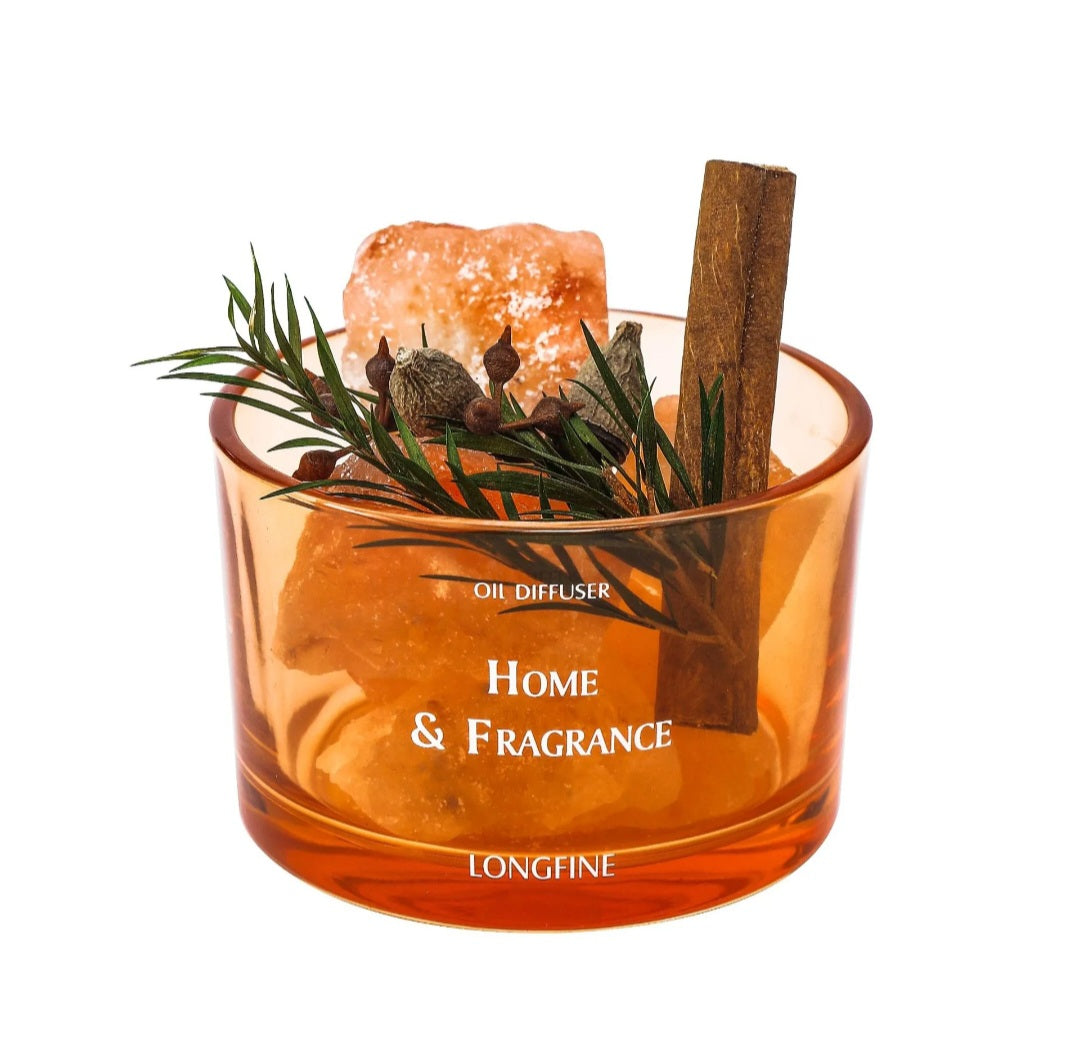 An amber glass oil diffuser candle with 'LONGFINE' branding, filled with orange wax and decorated with a cinnamon stick, rosemary sprig, and salt crystal, on a white background.